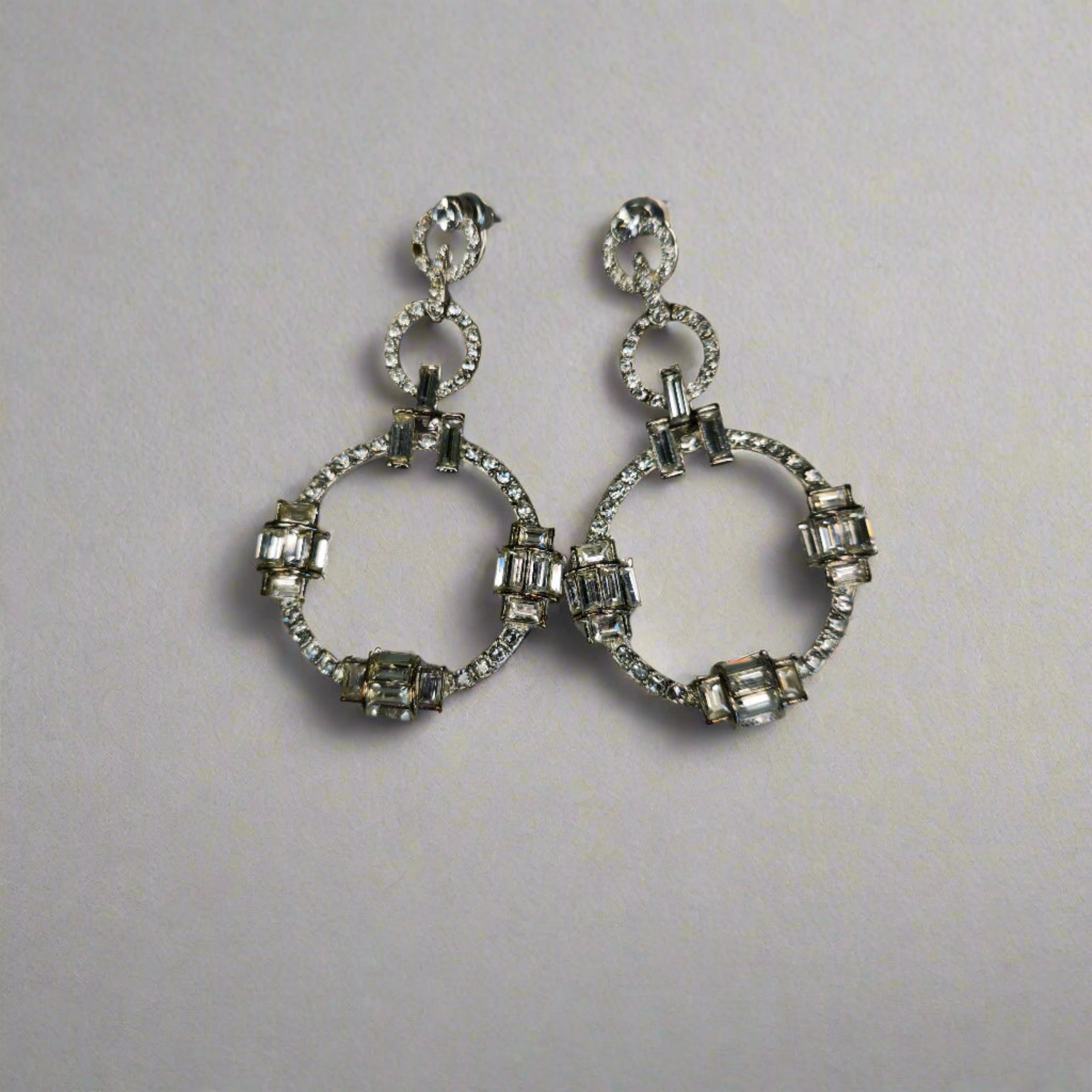 A pair of Oroton Silver Round Drop Earrings with intricate detailing and embedded clear stones.