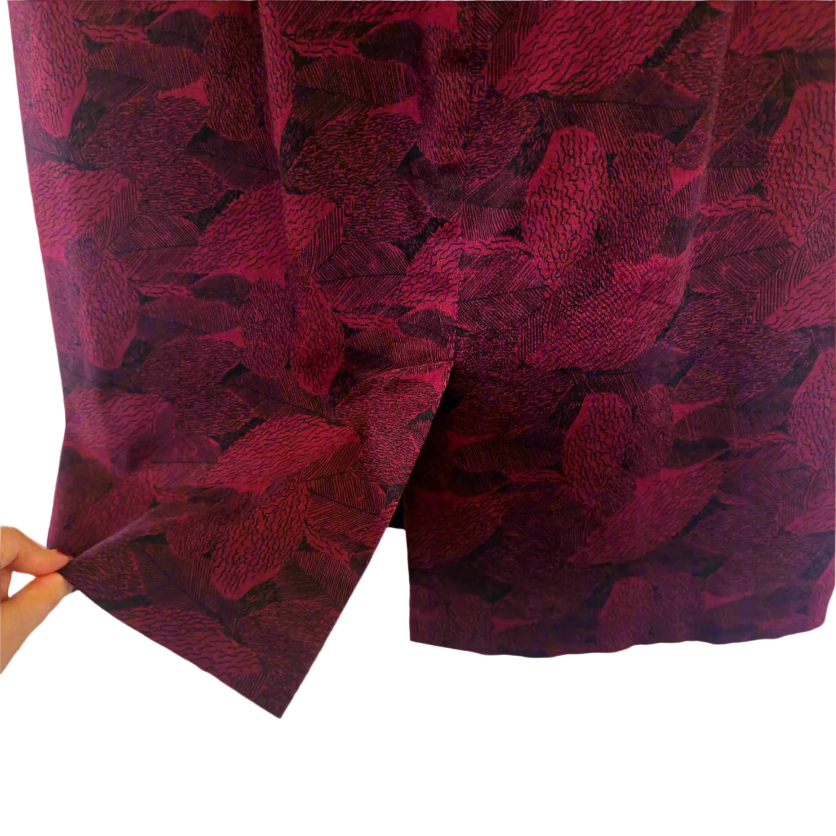 Close-up of a red textured fabric with a pattern, held against a light background.