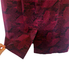 Close-up of a red textured fabric with a pattern, held against a light background.