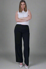 Woman wearing a white sleeveless top and black pants against a plain background