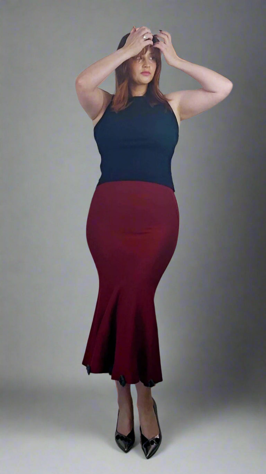 Person wearing a black top and red skirt against a plain background