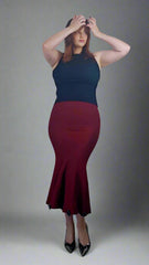 Person wearing a black top and red skirt against a plain background
