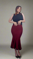 A person wearing a deep red knit skirt with a black floral pattern, reaching up to the thighs, paired with a black top and black shoes. The image shows only the lower half of the person's body, from the waist down.