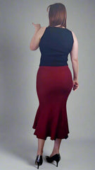 Woman wearing a black top and red skirt on a plain background