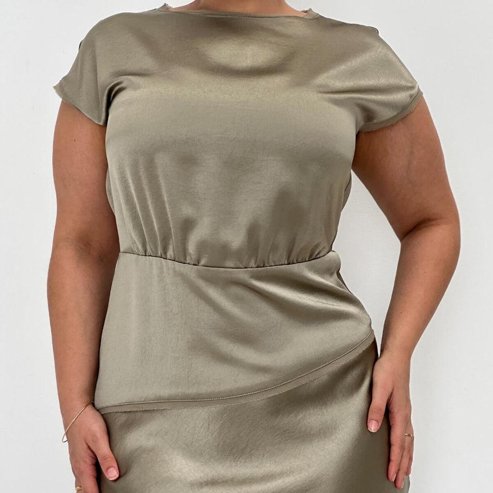 A model wearing an olive-colored, fitted knee-length dress with short, cap sleeves and a keyhole back neckline.