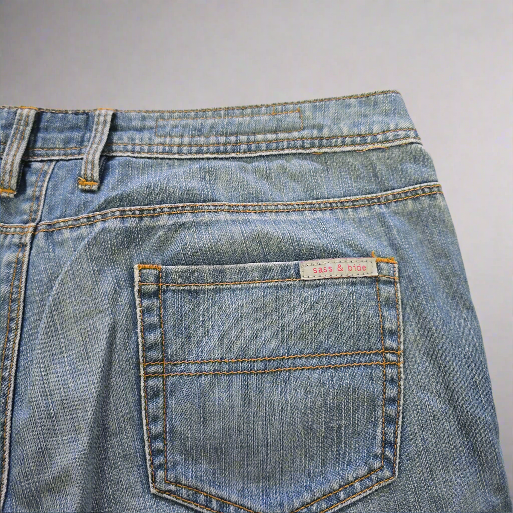 Close-up of a blue denim pocket with a brand label on a gray background
