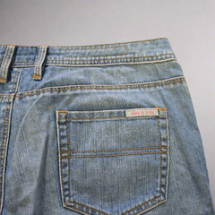 Close-up of a blue denim pocket with a brand label on a gray background