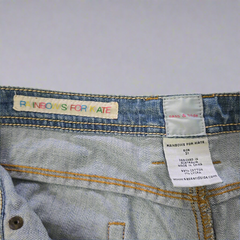 Close-up of denim jeans with 'Rainbows for Kate' label and brand tag on a light gray background