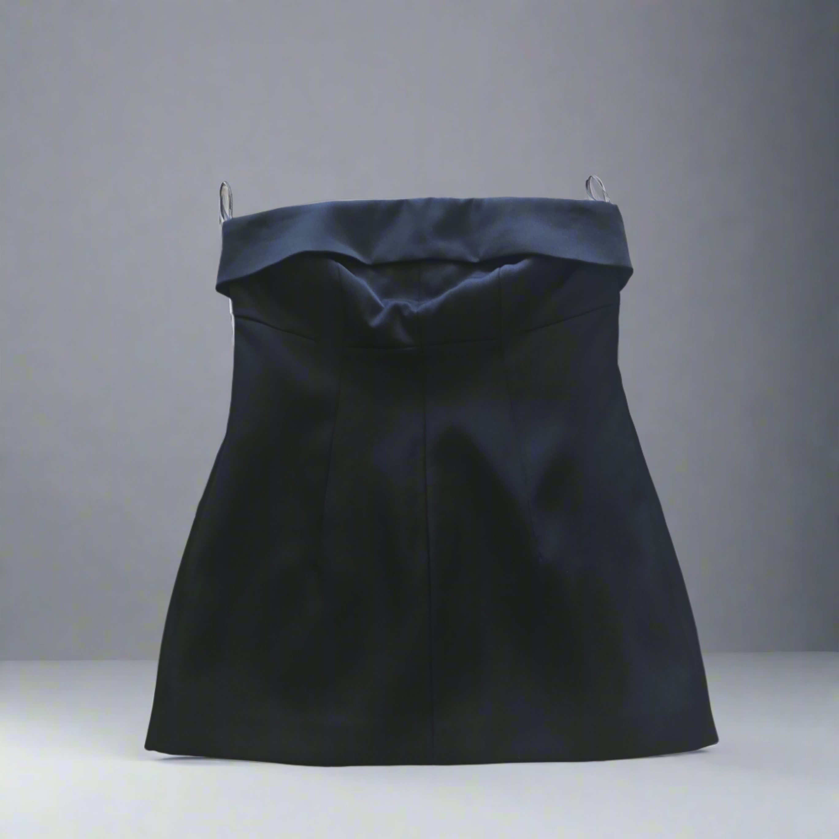 A black strapless corset top presented on a mannequin against a neutral background, showcasing the folded neckline and the fitted silhouette.