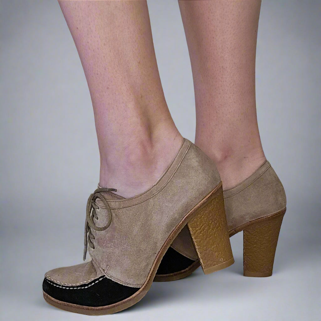 Beige suede shoes with wooden block heels on a neutral background