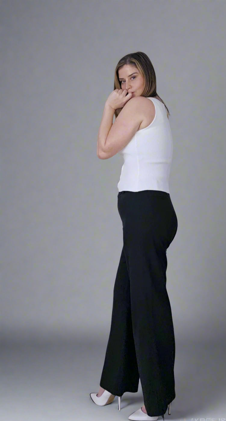 Woman wearing a white sleeveless top and black wide-leg pants on a gray background