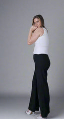 Woman wearing a white sleeveless top and black wide-leg pants on a gray background