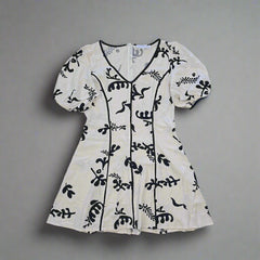 White garment with black floral patterns on a tiled floor