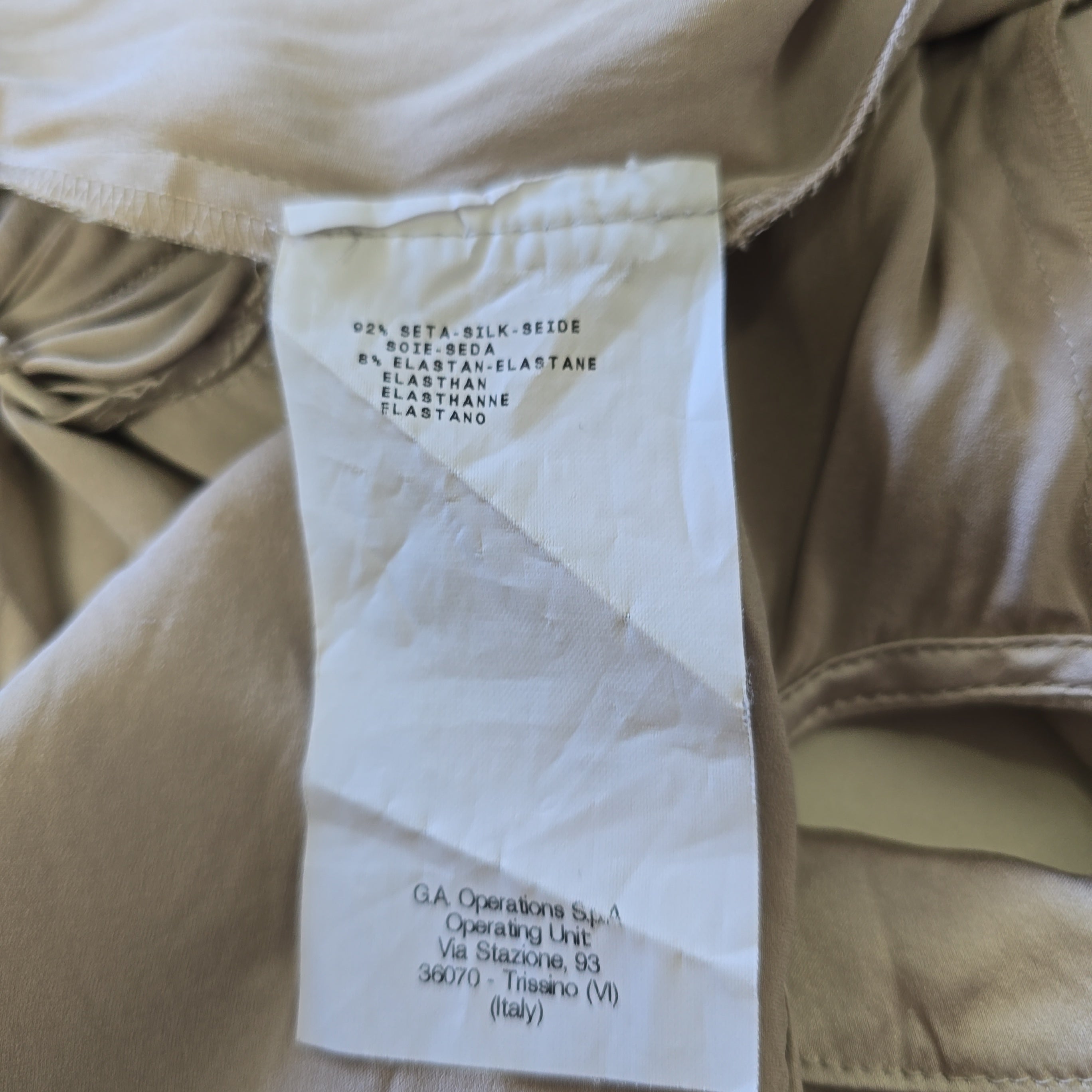 Close-up of beige pants with a label on a beige background