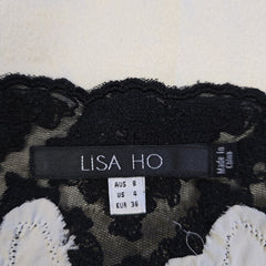 Close-up of a label on a black lace garment with floral details, featuring the brand 'Lisa Ho'.
