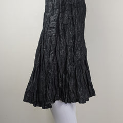 Black pleated skirt on a white mannequin arm against a light gray background