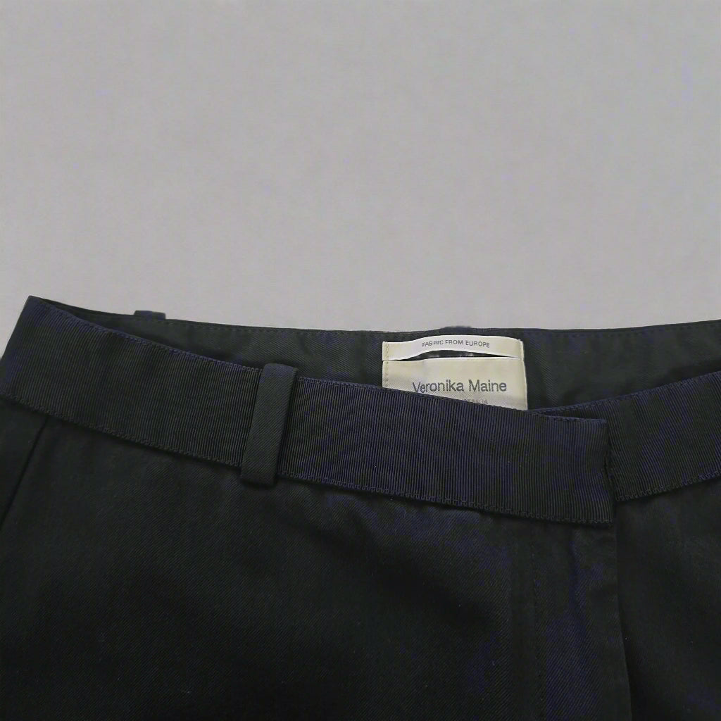 Black pants with a visible brand label on a beige background