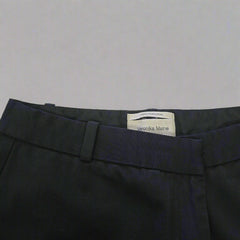 Black pants with a visible brand label on a beige background