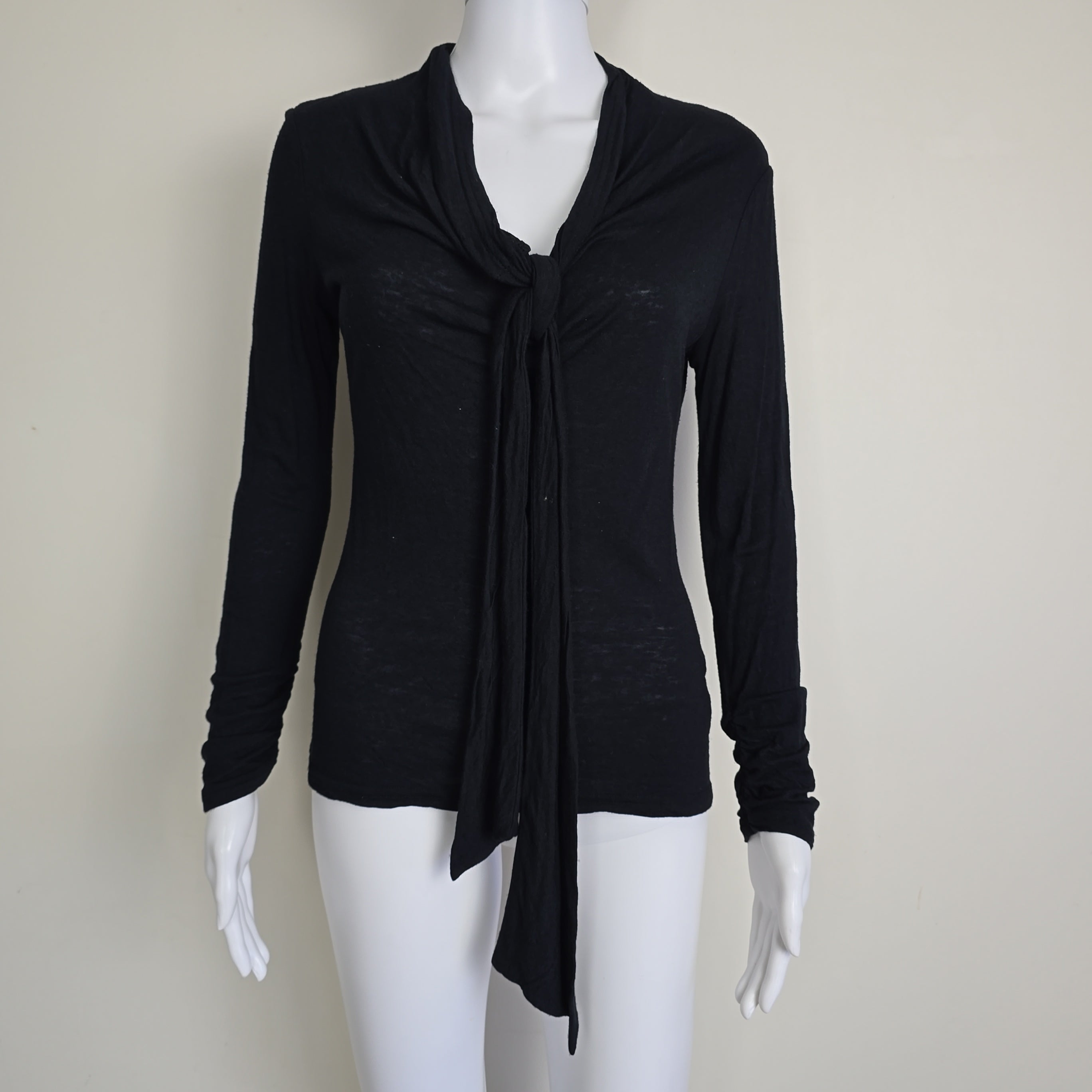 Black top on a mannequin against a plain background