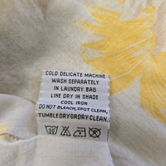 Fabric with yellow floral pattern and care label on a beige background