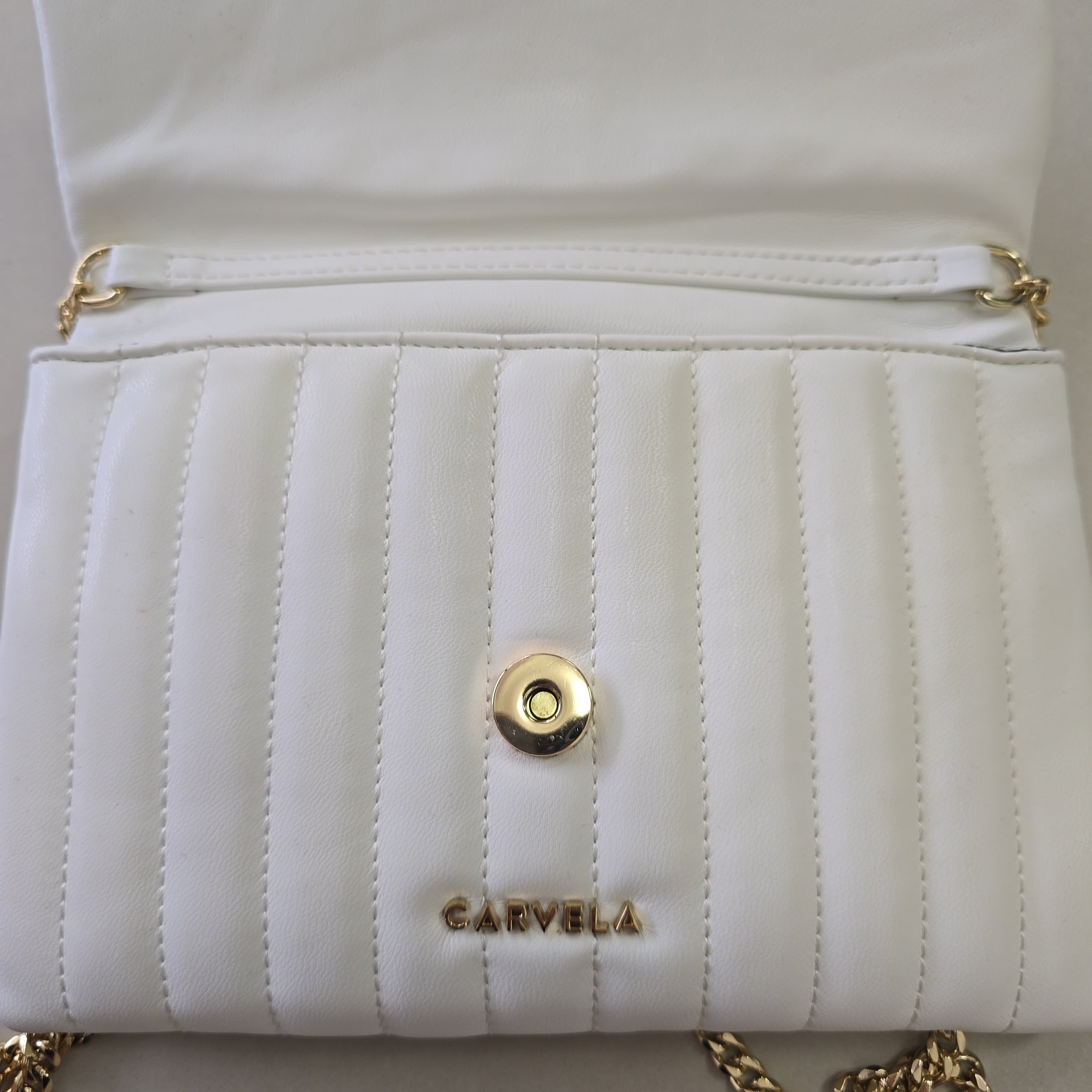 Close-up of a white quilted handbag with gold accents and 'Carvela' branding.