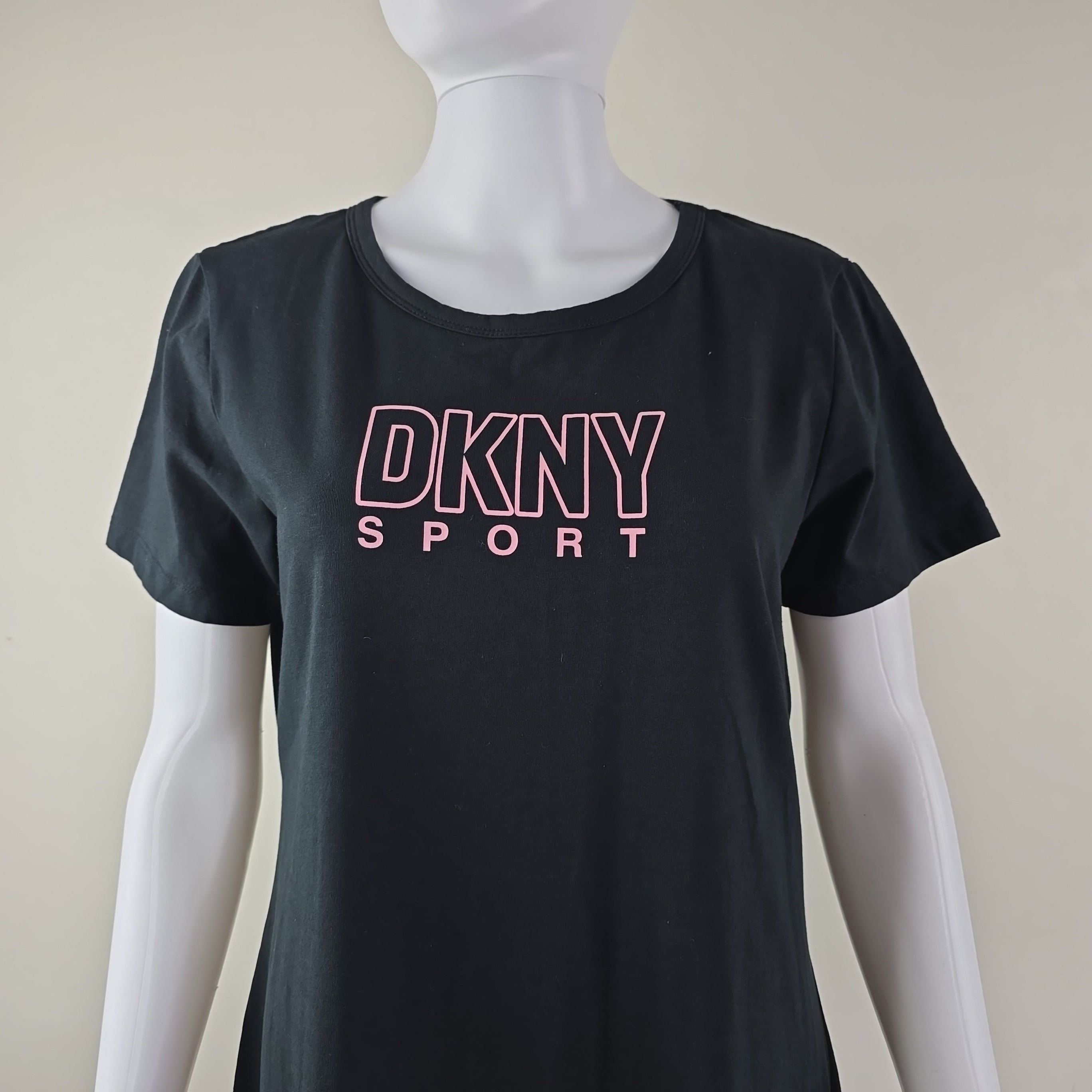 Black tank top with pink 'DKNY Sport' logo on a mannequin against a beige background
