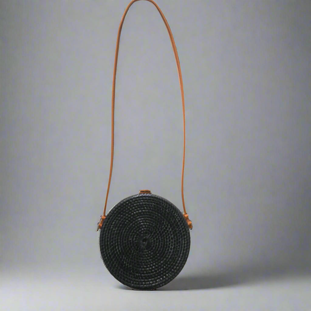 Black woven handbag with an orange strap on a tiled floor