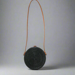 Black woven handbag with an orange strap on a tiled floor