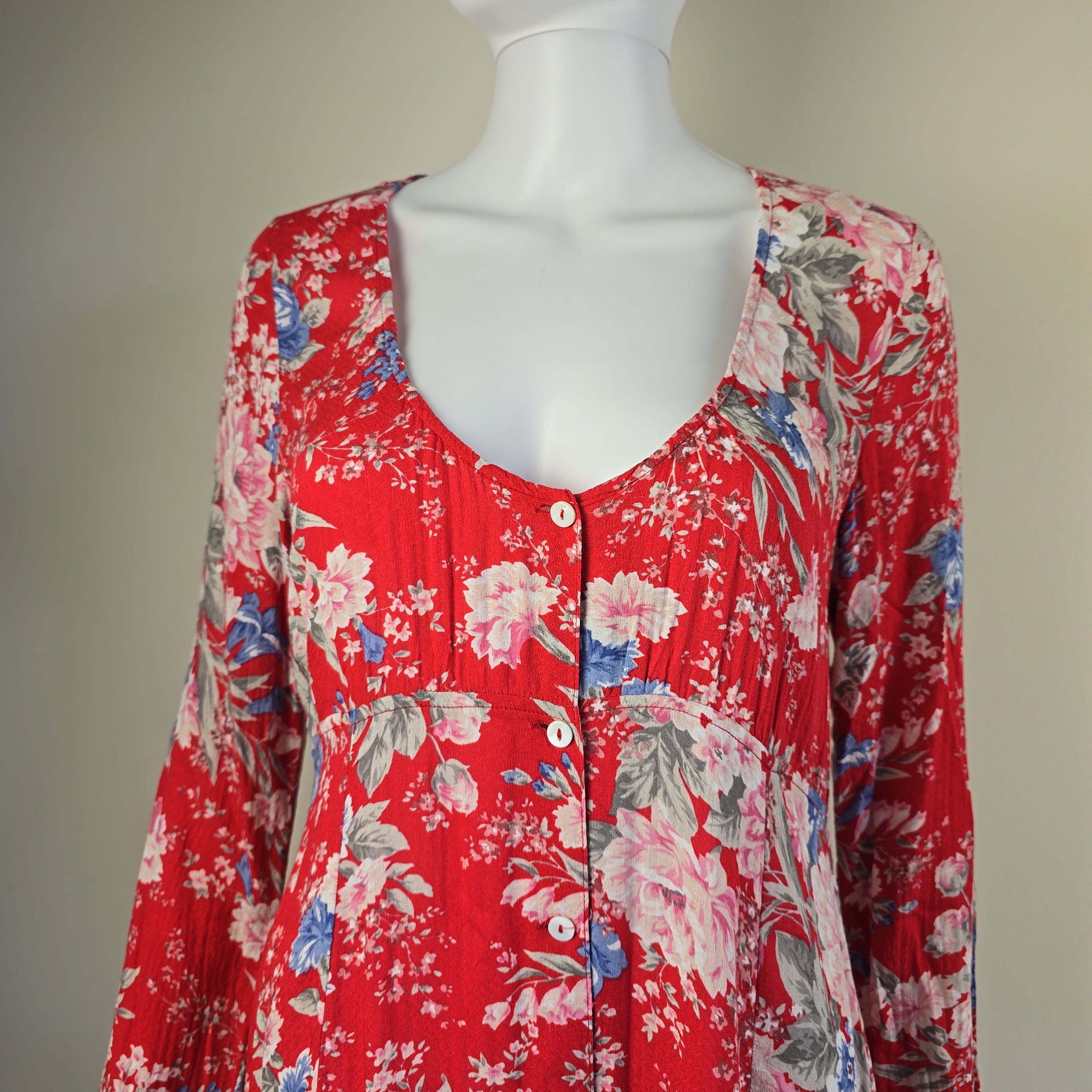 Red floral dress on a mannequin against a plain background