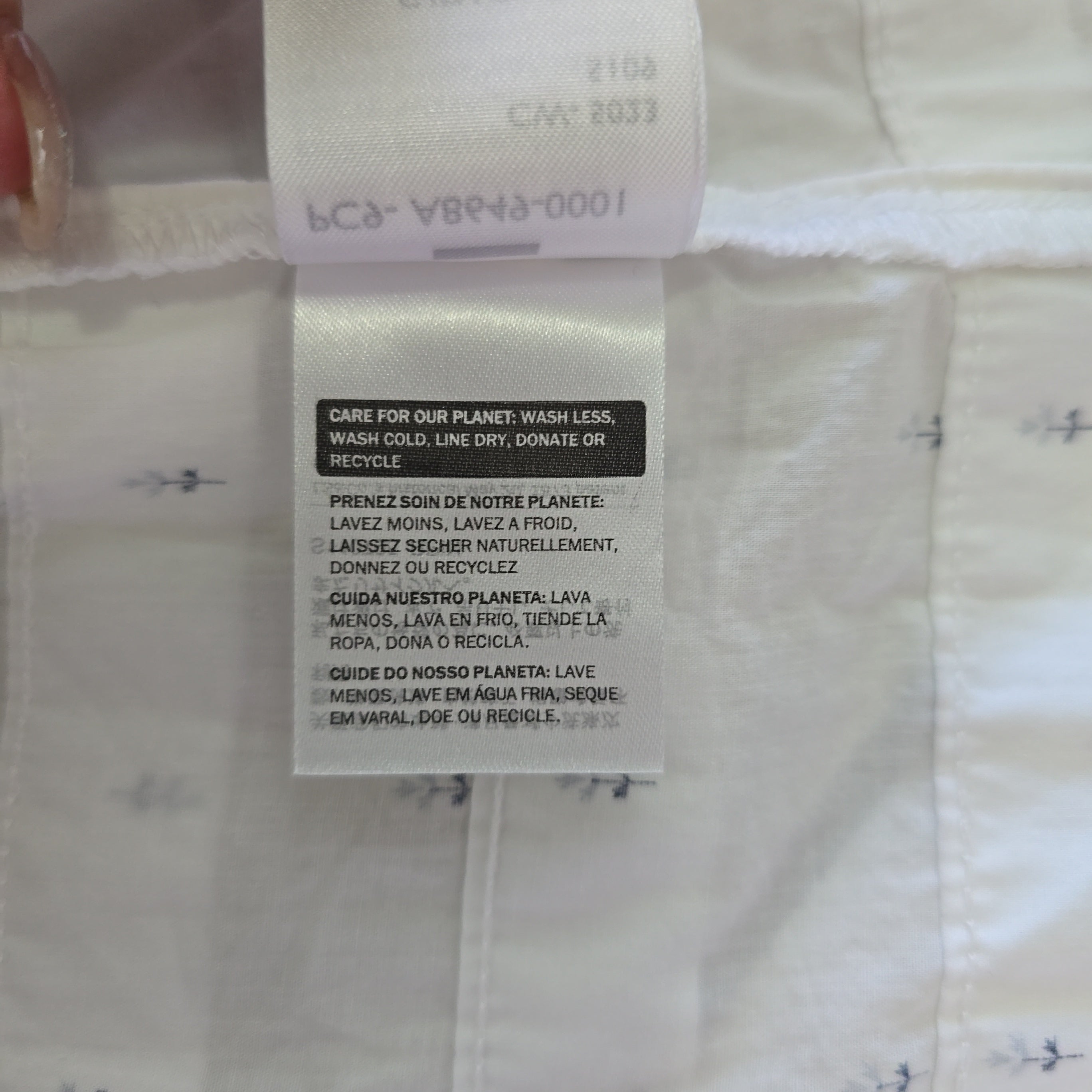 Close-up of a label on a white shirt with text and symbols.