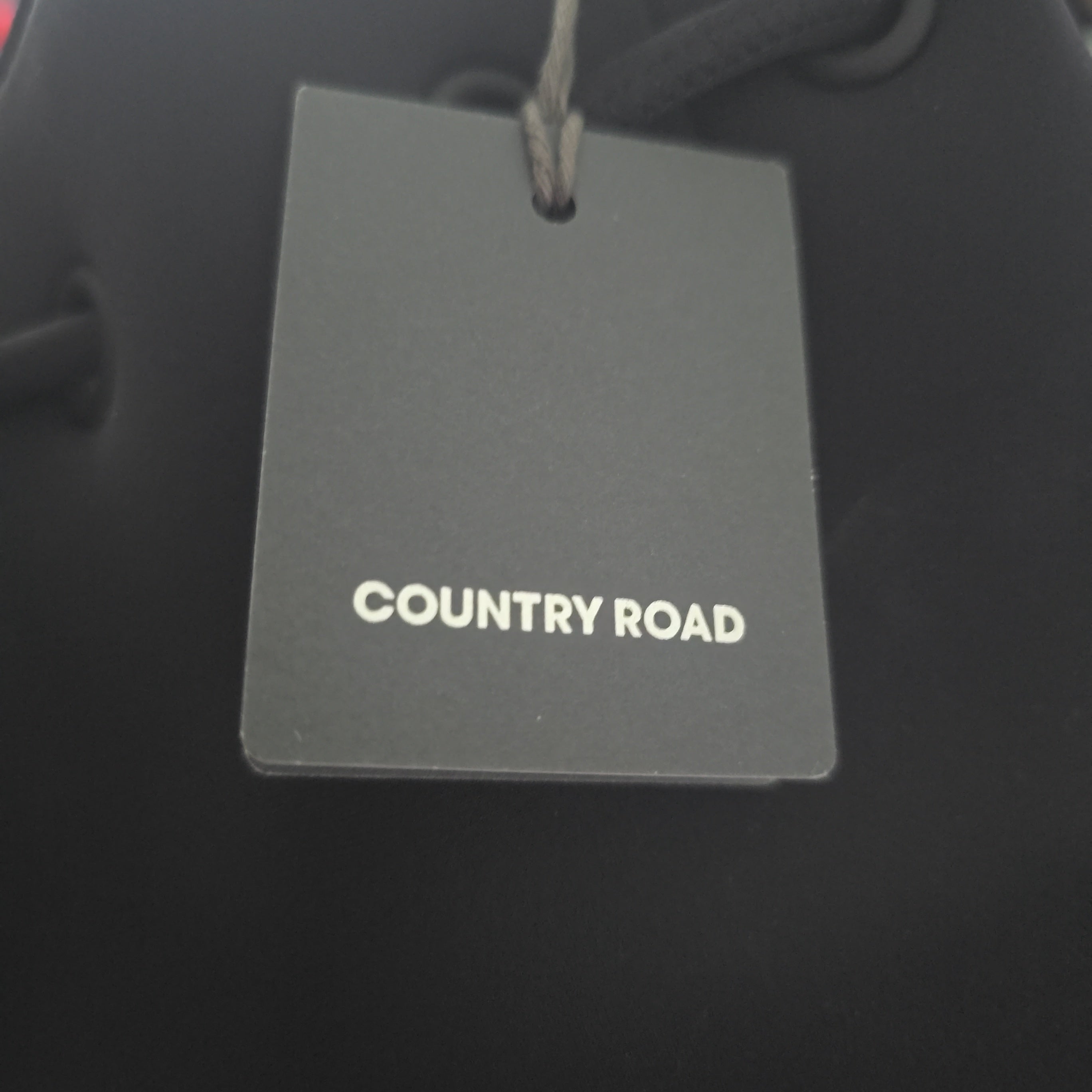 Gray tag with 'COUNTRY ROAD' text on a black background