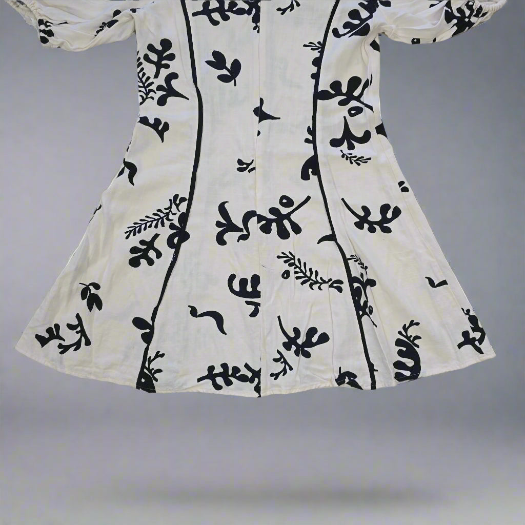 White garment with black floral patterns on a tiled floor