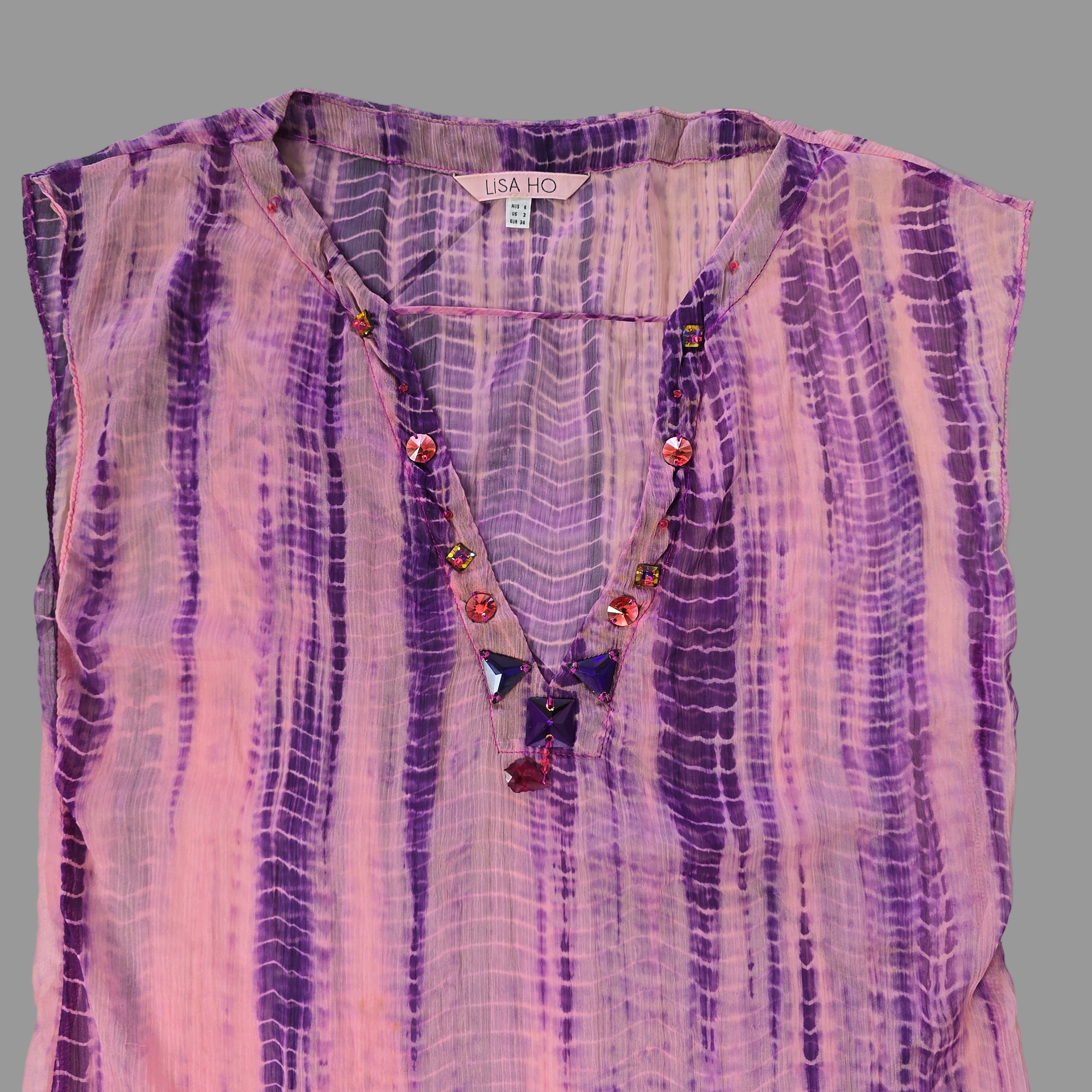 Purple and pink patterned fabric with beads on a tiled floor