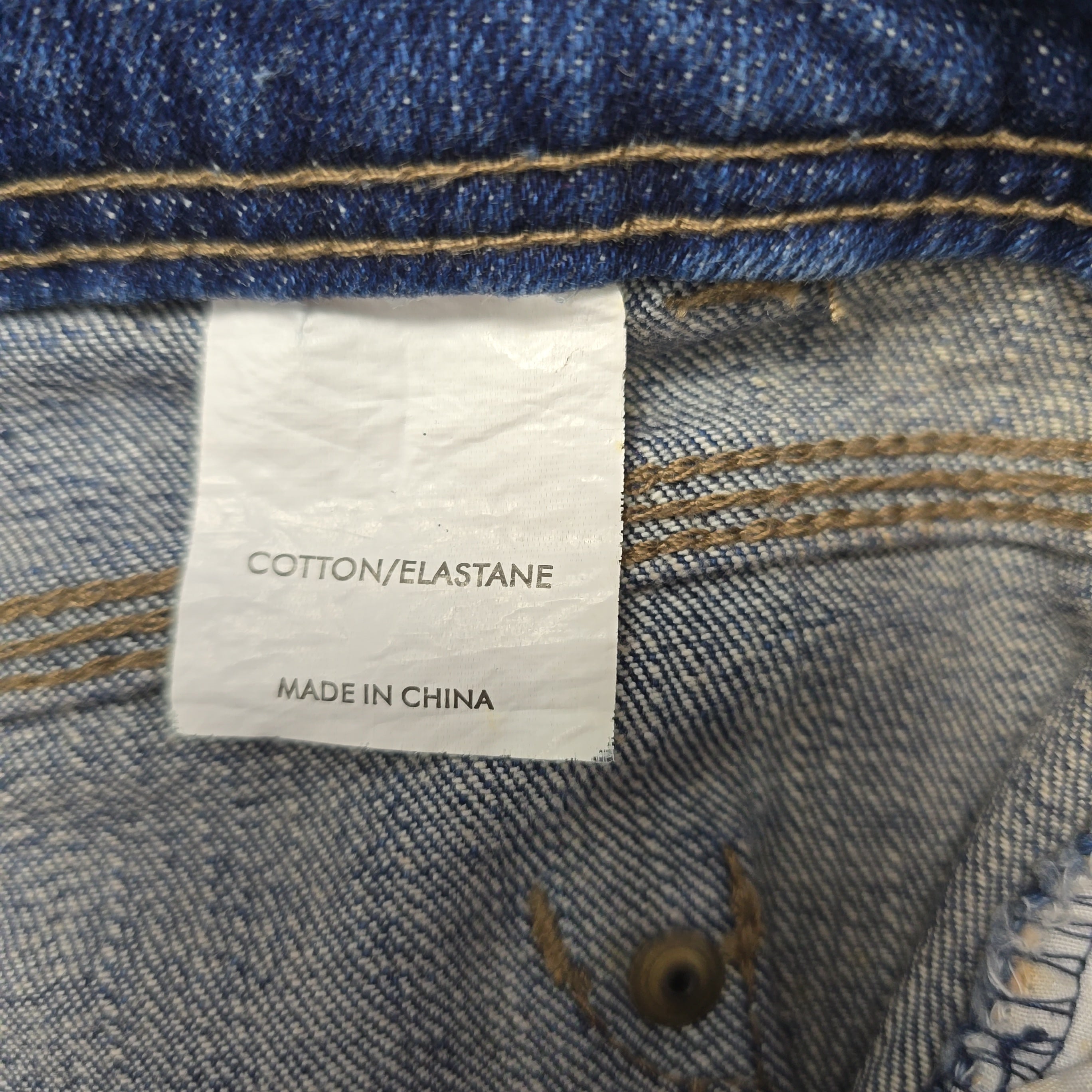 Close-up of a denim fabric with a label indicating 'Cotton/Elastane' and 'Made in China'.