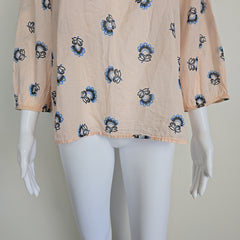 Mannequin draped with beige fabric featuring blue floral patterns on a plain background