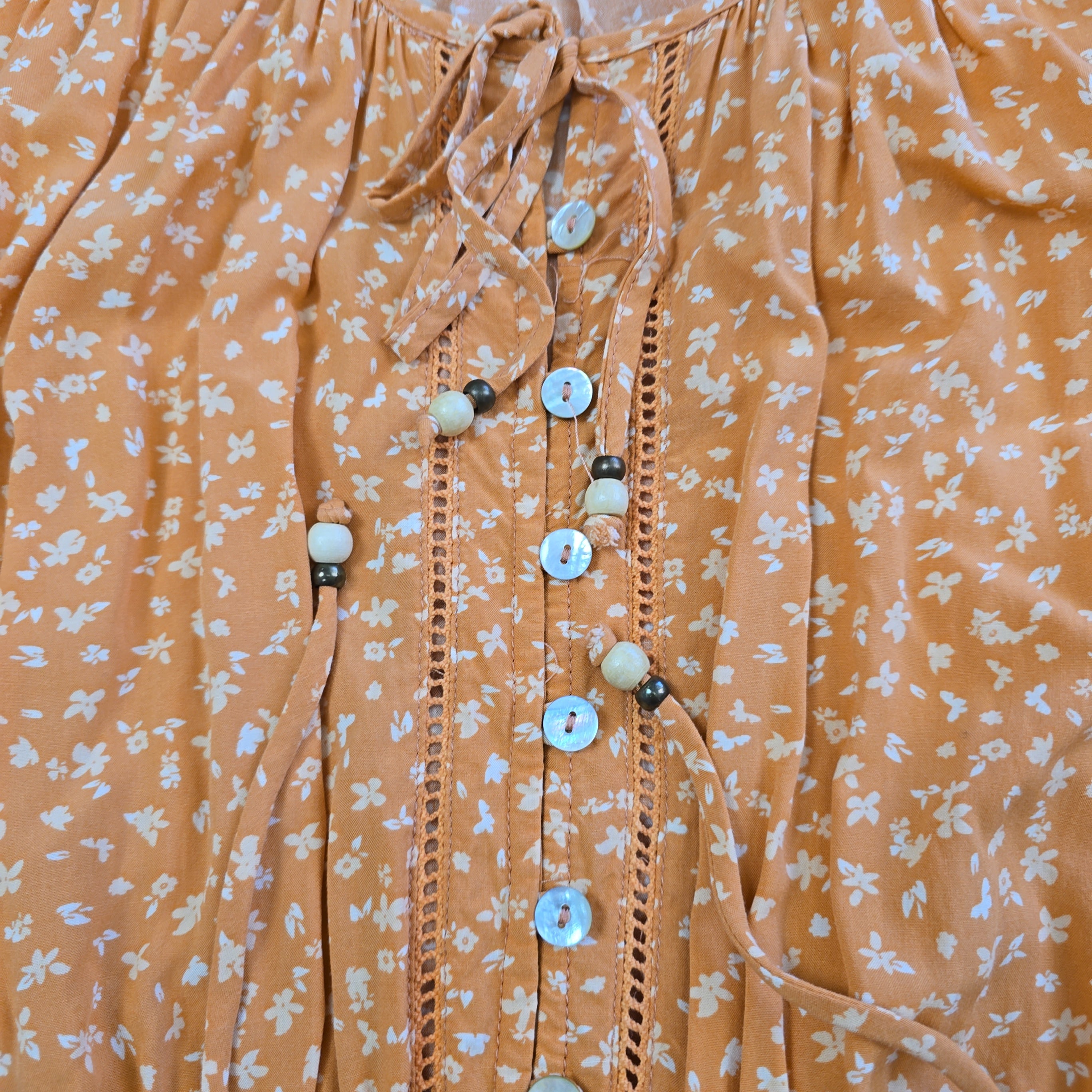 Close-up of a peach-colored fabric with white floral pattern and buttons.
