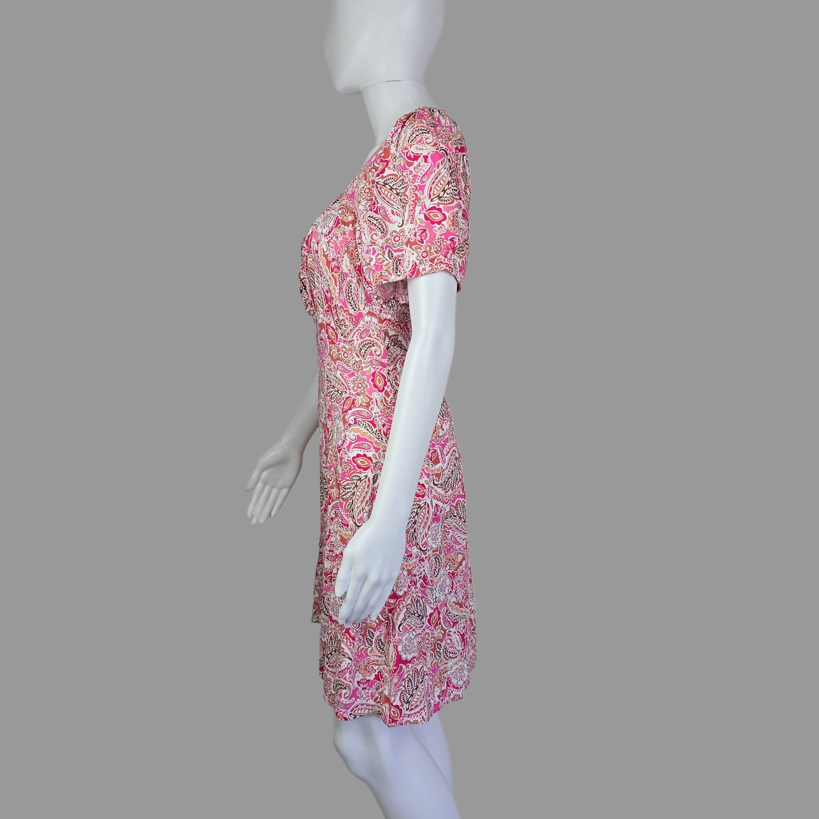 Mannequin wearing a pink floral dress with a plain background