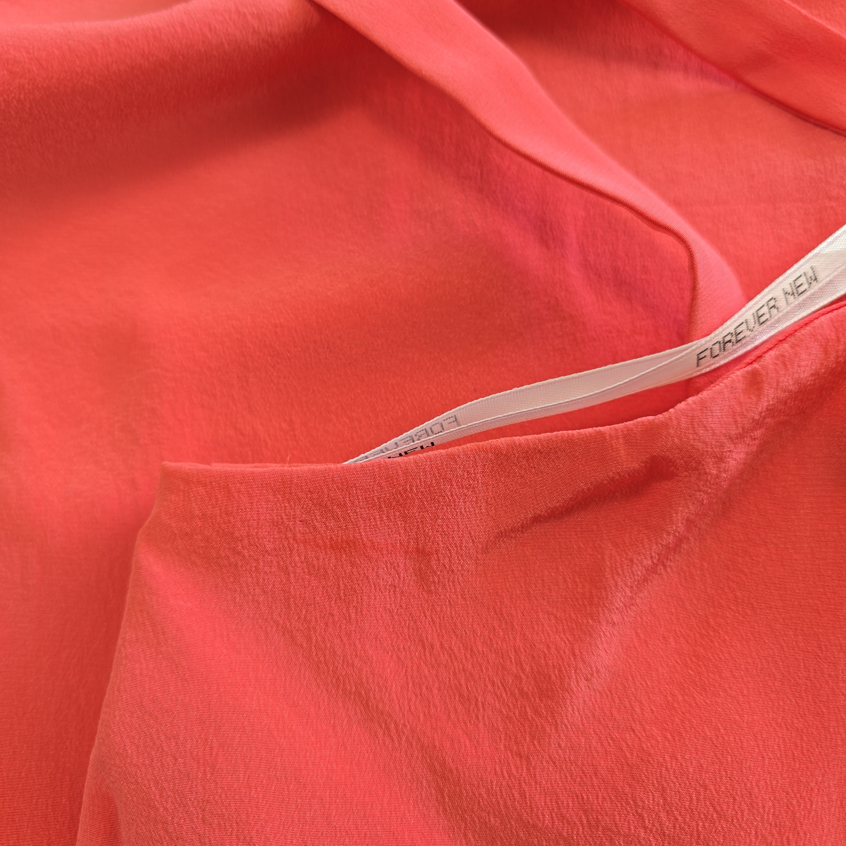 Close-up of pink fabric with a brand label.