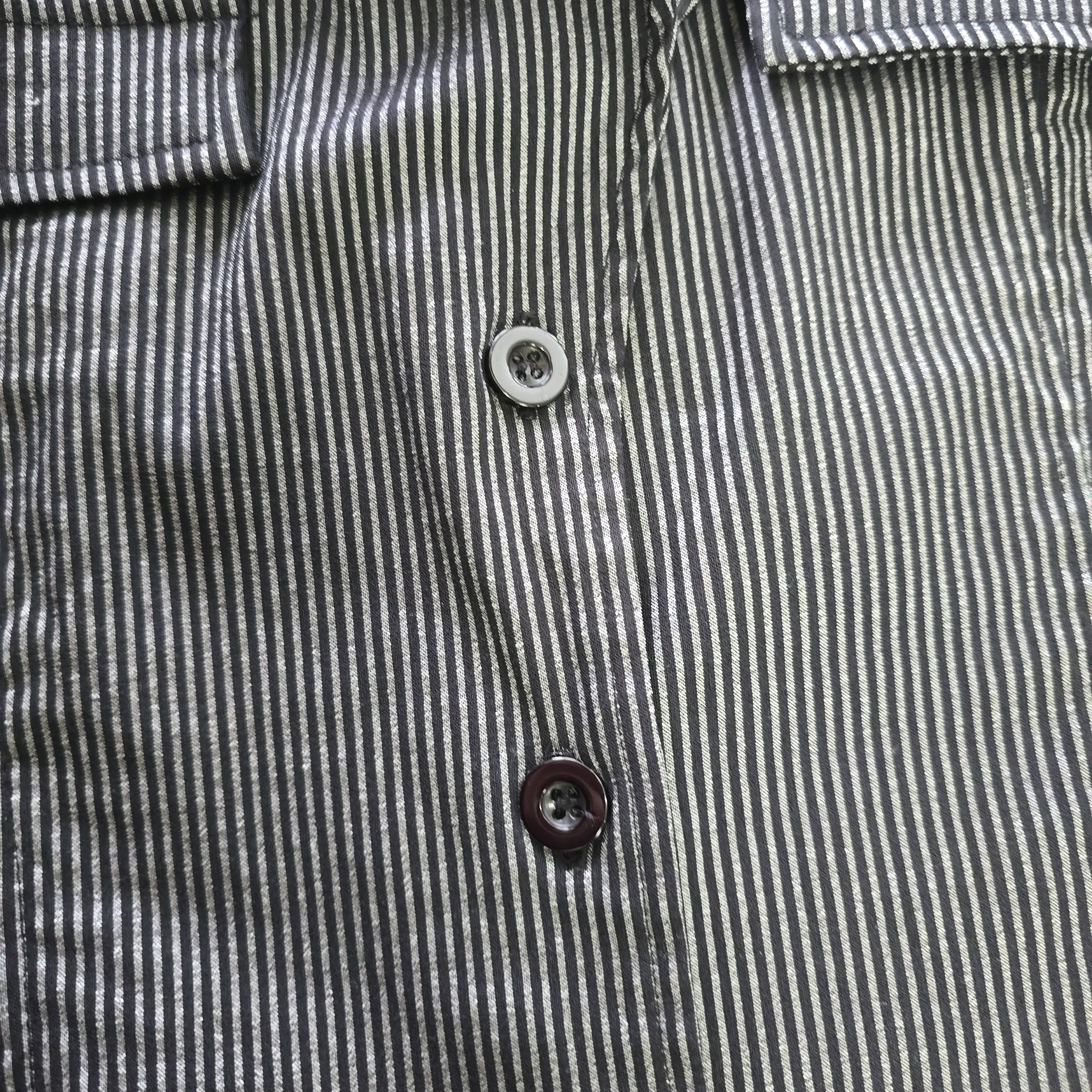 Close-up of a striped shirt with buttons on a plain background