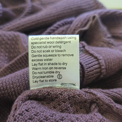 Close-up of a label on a purple knitted sweater with care instructions.