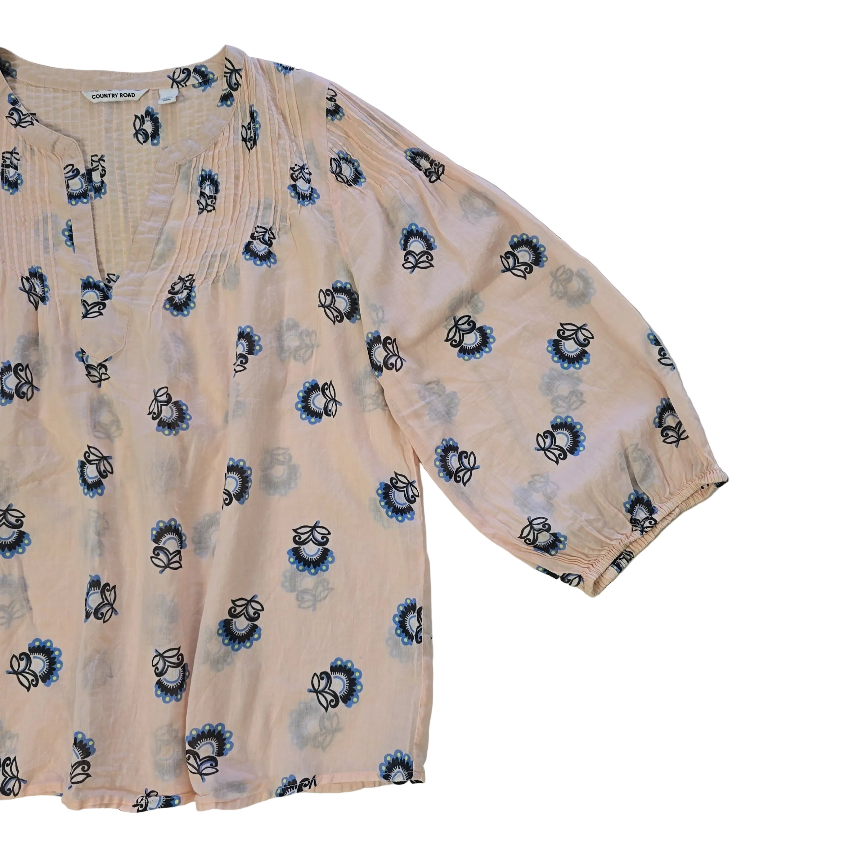 Folded peach-colored fabric with black and blue floral patterns on a light background