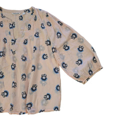 Folded peach-colored fabric with black and blue floral patterns on a light background