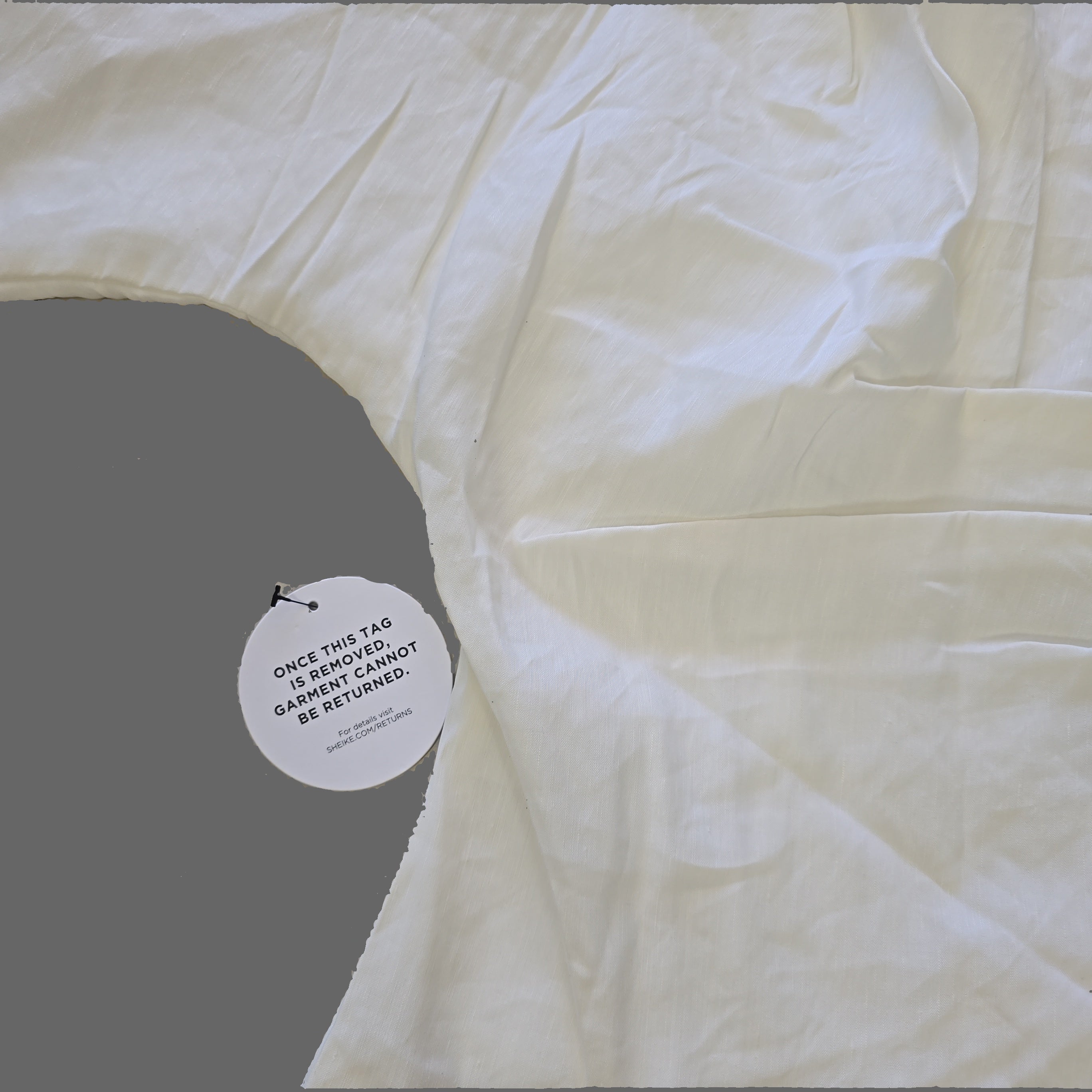 Close-up of a white garment with a label on a beige surface