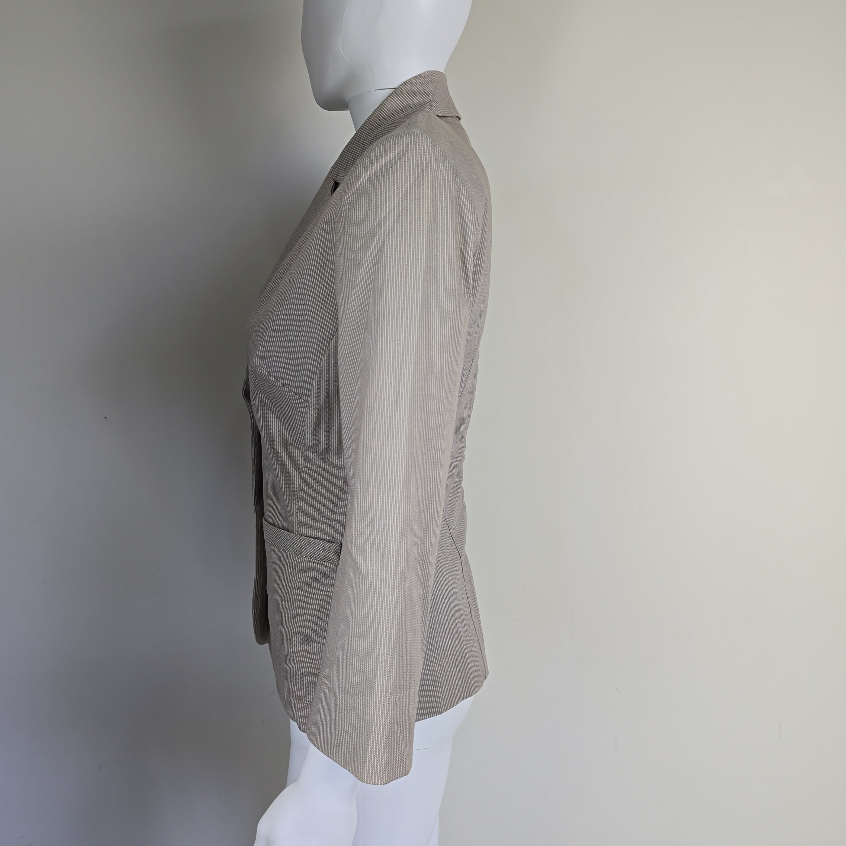 Mannequin wearing a light gray suit jacket on a plain background