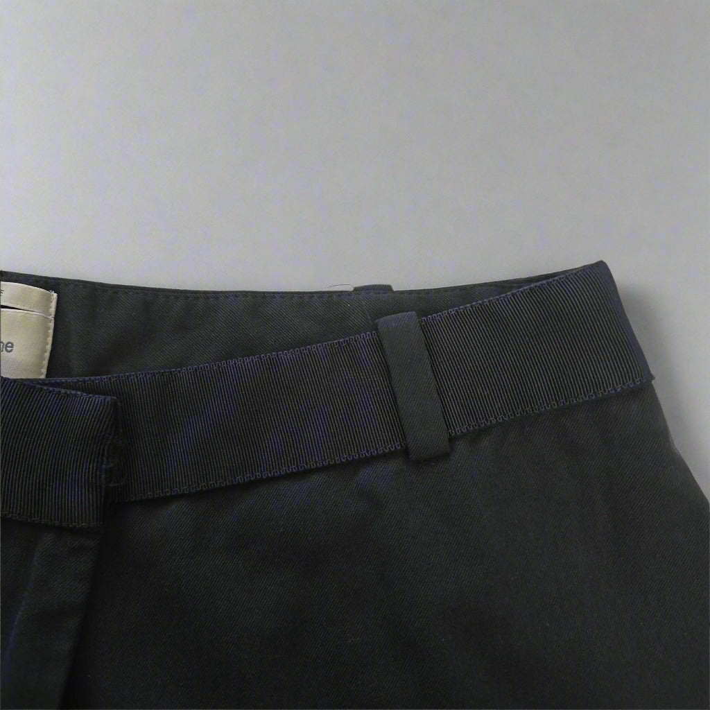Close-up of a black Pants with a strap on a beige background