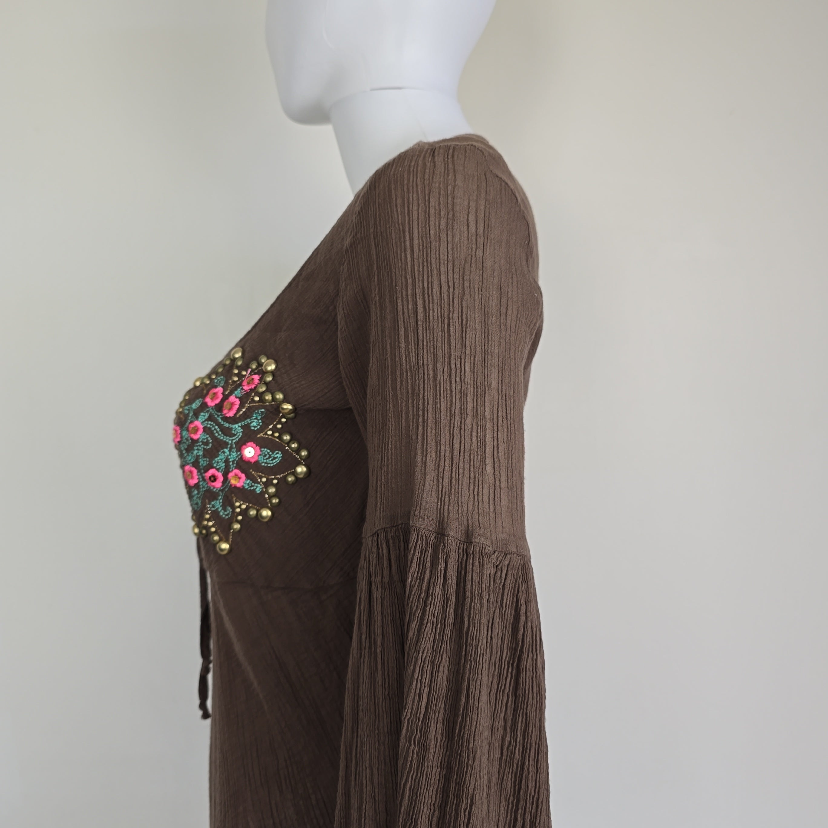Brown fabric with floral embroidery on a mannequin against a white background