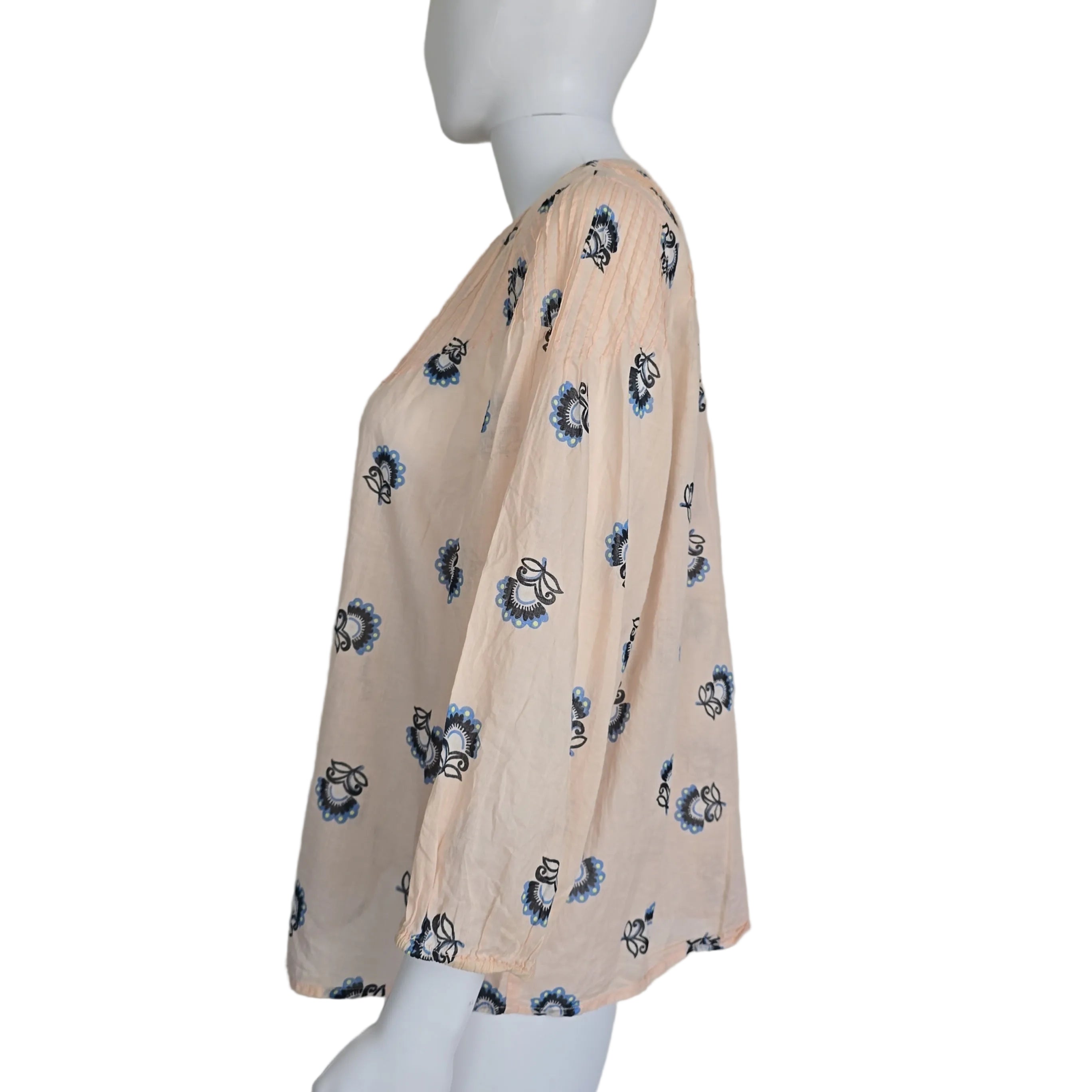 Mannequin wearing a beige fabric top with blue floral patterns on a plain background
