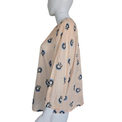 Mannequin wearing a beige fabric top with blue floral patterns on a plain background