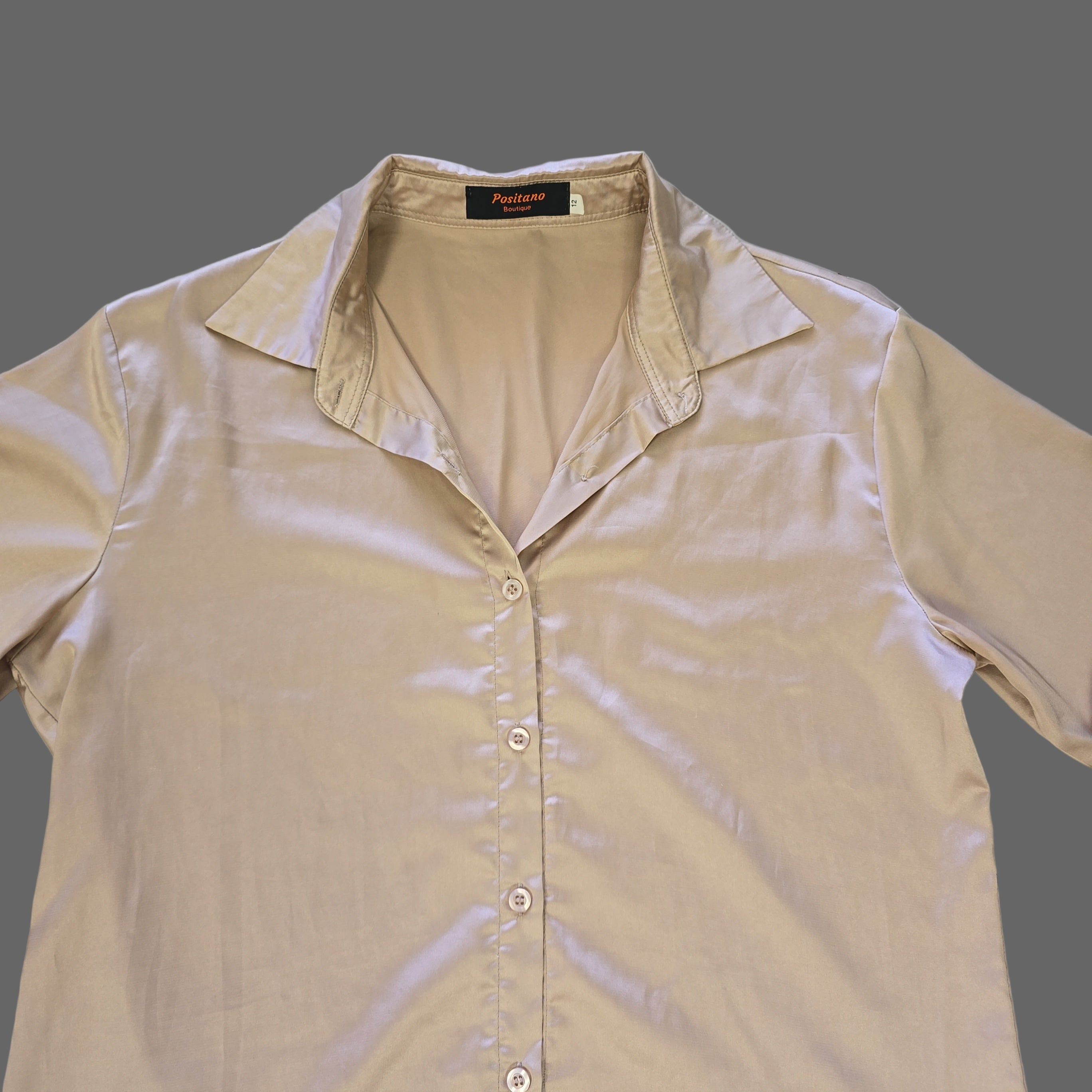 Beige shirt with a brand label on a tiled floor