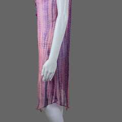 Purple and pink fabric draped over a white surface with a hand touching it.